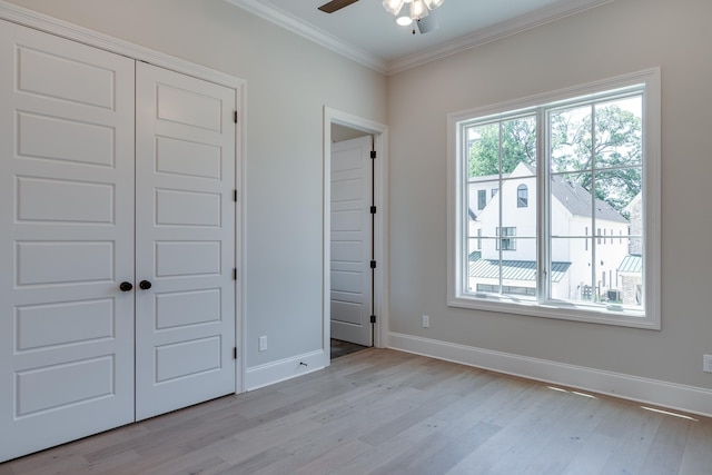 unfurnished bedroom featuring a closet, ceiling fan, crown molding, and light wood-type flooring