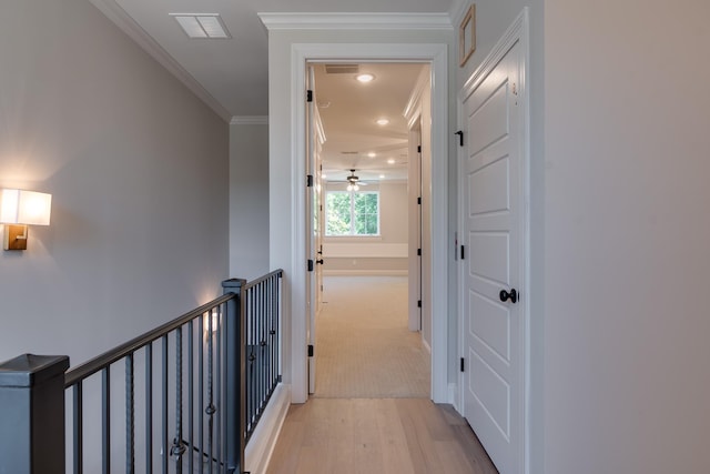 corridor with light hardwood / wood-style floors and ornamental molding