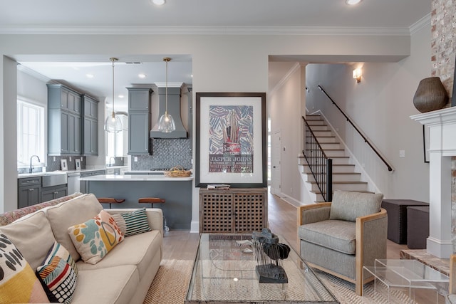 living room featuring sink, light wood-type flooring, and ornamental molding