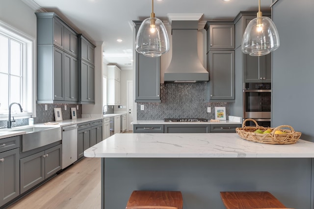 kitchen featuring gray cabinetry, sink, stainless steel appliances, decorative light fixtures, and custom exhaust hood