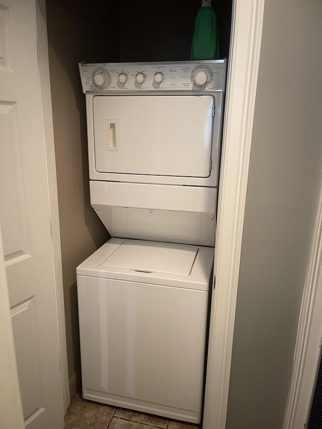 laundry area with stacked washer / dryer and light tile floors