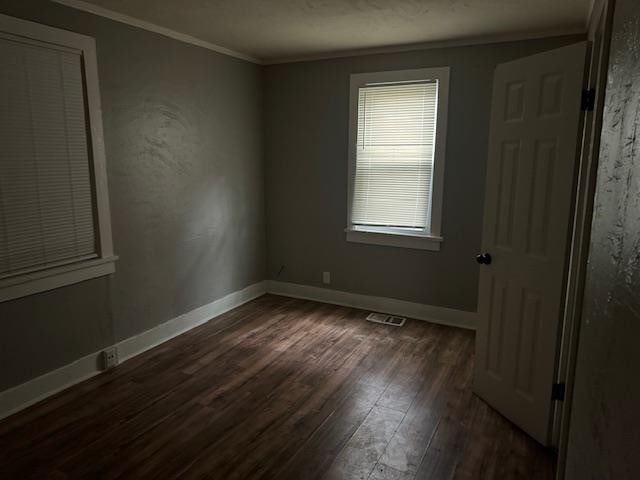 empty room with crown molding and dark hardwood / wood-style floors