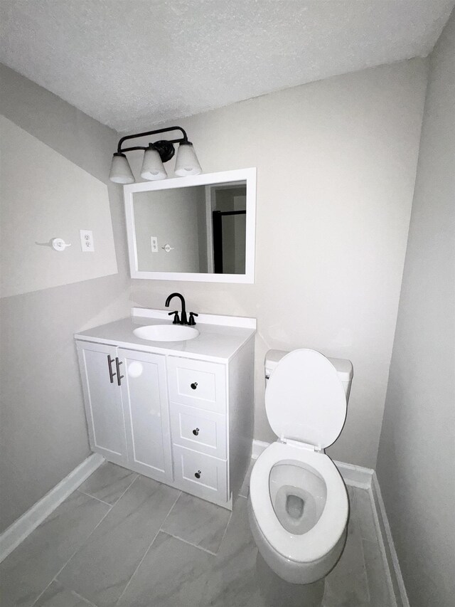 bathroom featuring vanity, a textured ceiling, and toilet