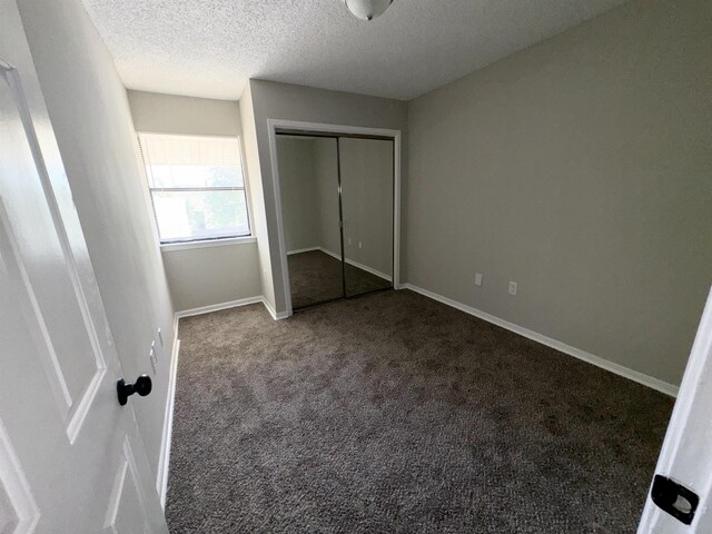 unfurnished bedroom with carpet, a textured ceiling, and a closet