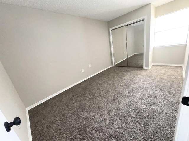 unfurnished bedroom with carpet flooring, a textured ceiling, and a closet