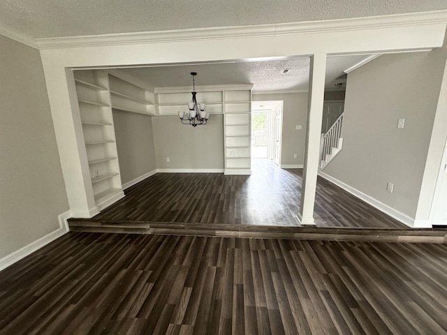 interior space featuring dark wood-type flooring, crown molding, built in shelves, a textured ceiling, and a notable chandelier