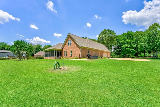 back of house featuring a lawn, a garage, and a sunroom