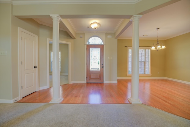 carpeted foyer featuring crown molding and a notable chandelier