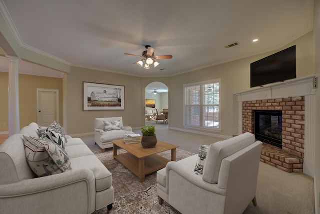 carpeted living room featuring a brick fireplace, crown molding, and ceiling fan