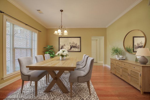 dining room with crown molding, a chandelier, and light hardwood / wood-style flooring