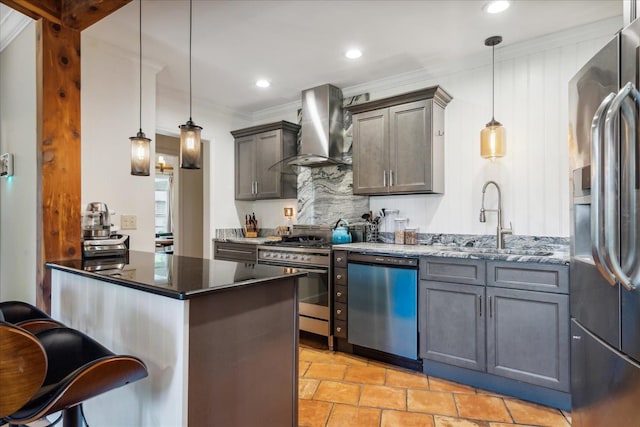 kitchen featuring wall chimney range hood, hanging light fixtures, appliances with stainless steel finishes, sink, and light tile floors