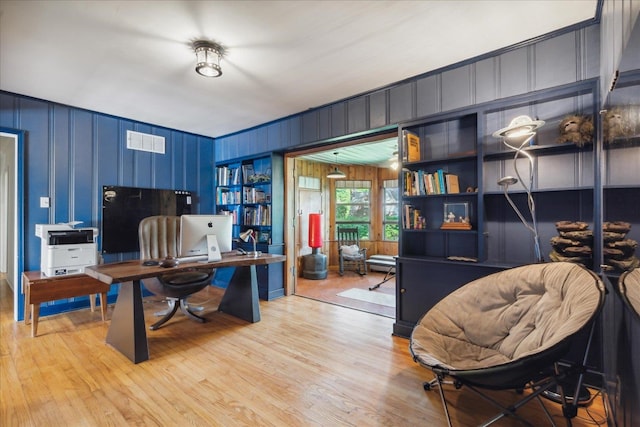 home office featuring light hardwood / wood-style floors and wood walls