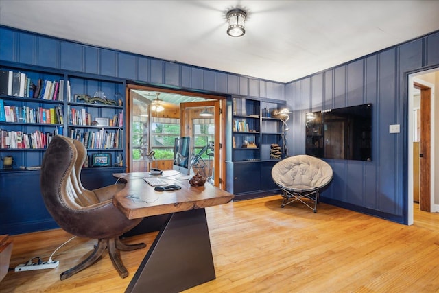 office space with built in features, wood walls, and light wood-type flooring