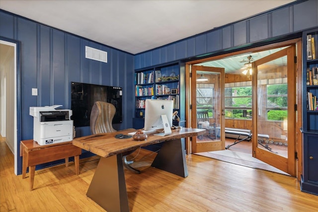 home office with wood walls, built in features, and light hardwood / wood-style floors