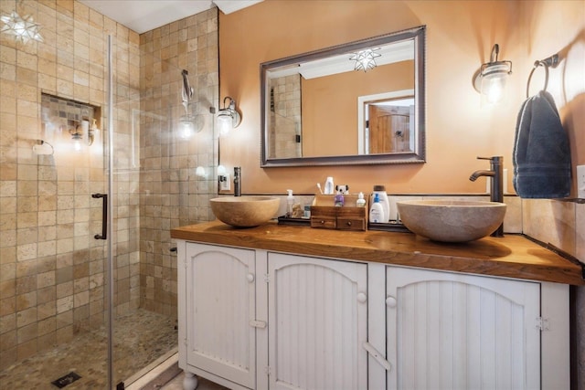 bathroom featuring a shower with shower door, vanity with extensive cabinet space, and double sink