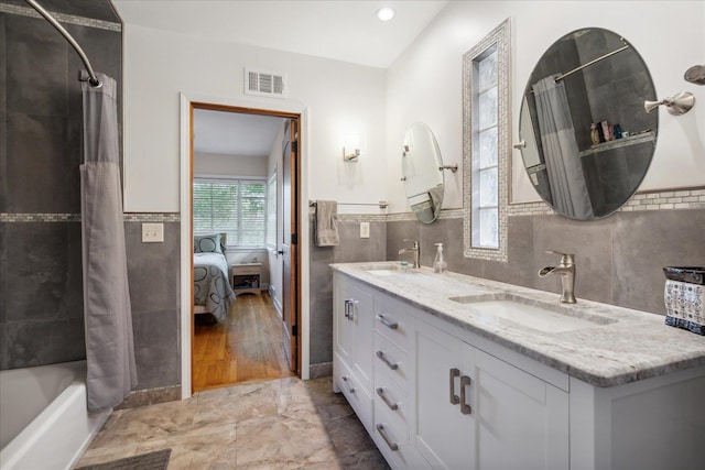 bathroom featuring tile walls, backsplash, shower / bathtub combination with curtain, dual bowl vanity, and hardwood / wood-style flooring