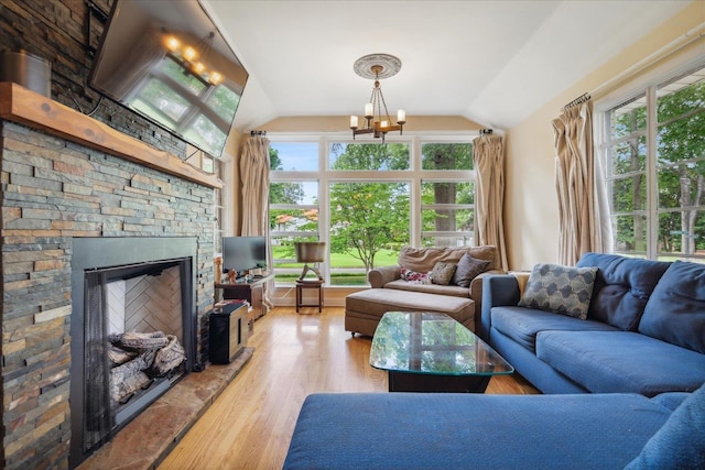 living room featuring a notable chandelier, lofted ceiling, a fireplace, and hardwood / wood-style flooring