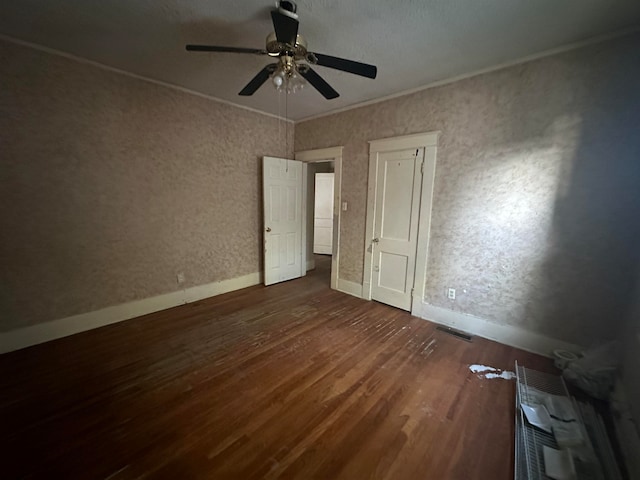 unfurnished bedroom featuring ceiling fan, ornamental molding, and dark wood-type flooring