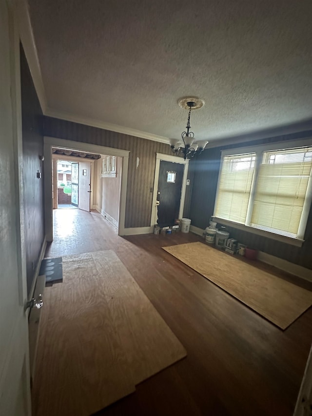 unfurnished bedroom featuring a notable chandelier, hardwood / wood-style flooring, crown molding, and a textured ceiling