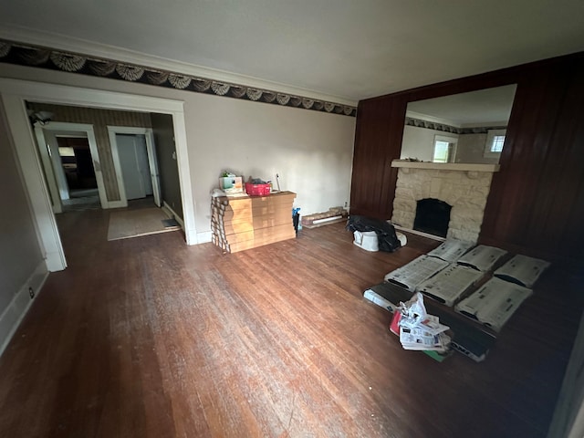 living room featuring a stone fireplace, dark hardwood / wood-style flooring, and crown molding