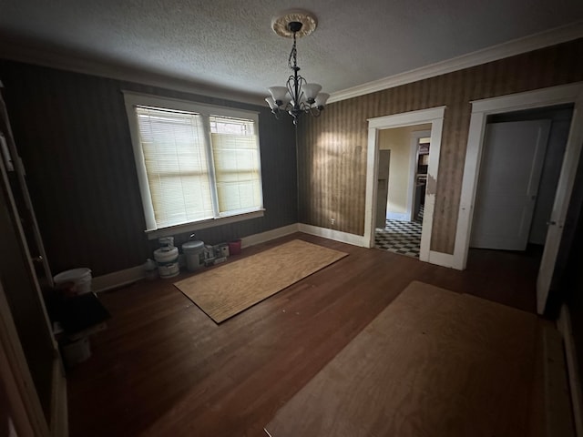 unfurnished dining area featuring a notable chandelier, a textured ceiling, crown molding, and dark tile floors