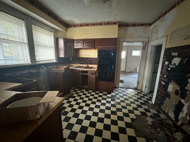 kitchen with black double oven, stainless steel gas cooktop, backsplash, dark tile flooring, and dark brown cabinets