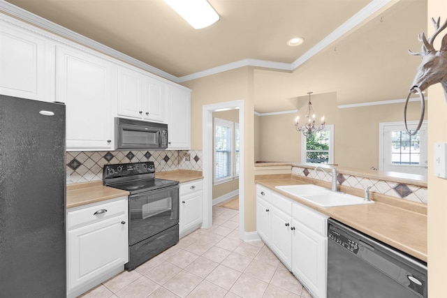 kitchen with pendant lighting, sink, crown molding, white cabinetry, and black appliances