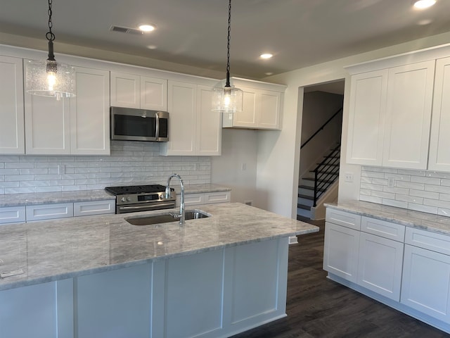 kitchen with white cabinetry, hanging light fixtures, stainless steel appliances, and light stone counters