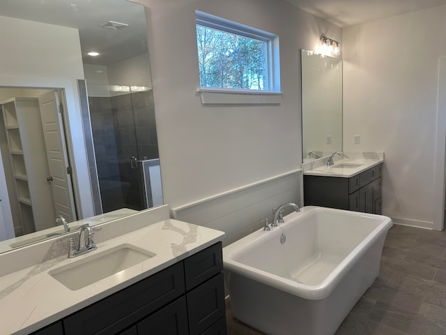 full bath with a stall shower, two vanities, a sink, and a freestanding bath