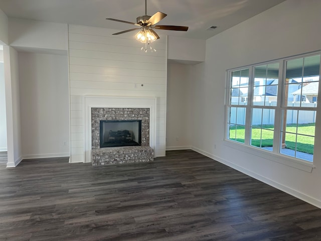 unfurnished living room with baseboards, visible vents, a fireplace with raised hearth, and dark wood-type flooring