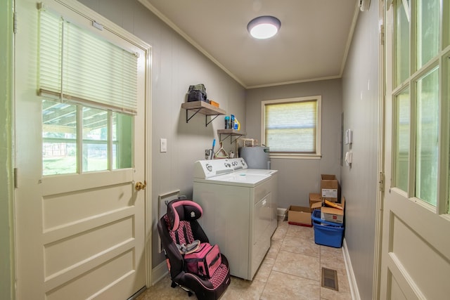 laundry room with a wealth of natural light, crown molding, light tile patterned flooring, and water heater