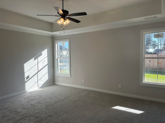 carpeted spare room featuring a tray ceiling, ceiling fan, and crown molding