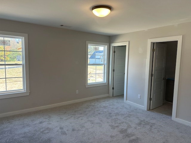 unfurnished bedroom with light colored carpet and a closet