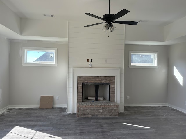 unfurnished living room featuring dark hardwood / wood-style floors, ceiling fan, and a brick fireplace