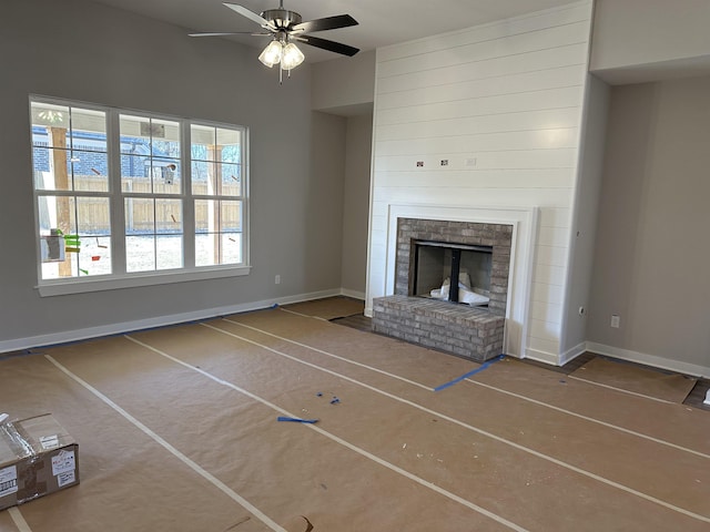 unfurnished living room with a brick fireplace and ceiling fan