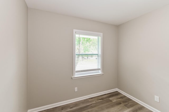unfurnished room with baseboards and dark wood-type flooring