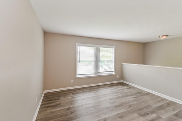 spare room featuring baseboards and wood finished floors