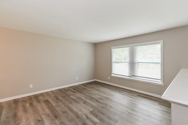 unfurnished room with baseboards and wood finished floors