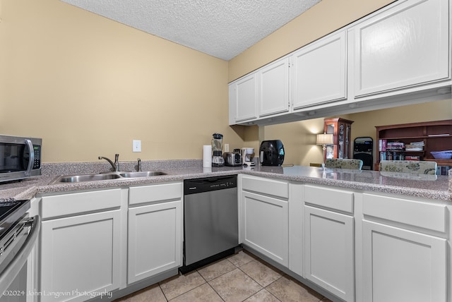 kitchen featuring a textured ceiling, white cabinetry, stainless steel appliances, sink, and light tile patterned floors