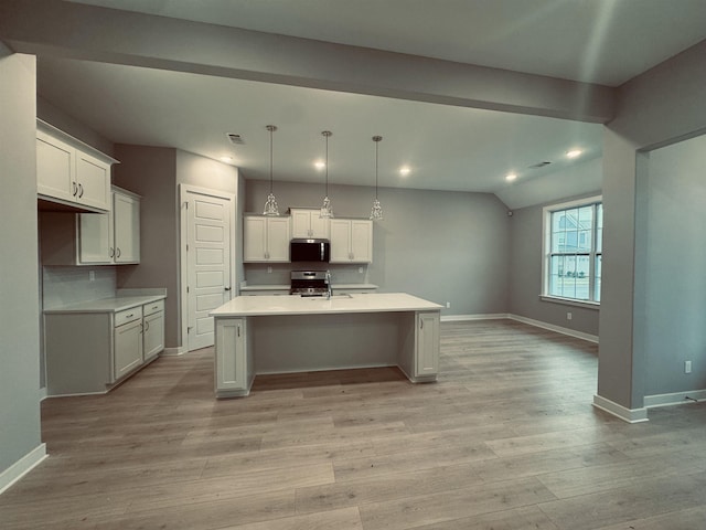 kitchen featuring a center island with sink, appliances with stainless steel finishes, light countertops, and pendant lighting