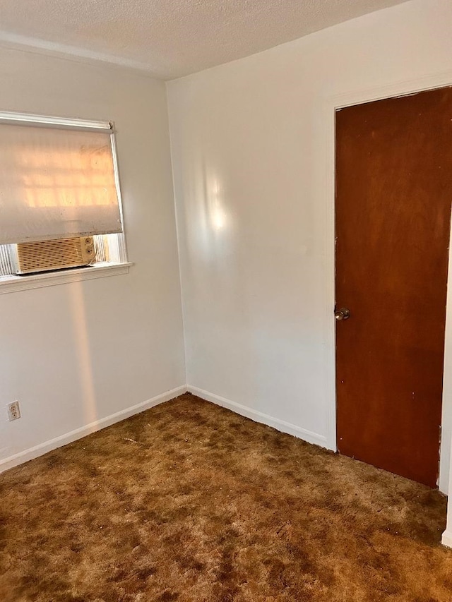 carpeted spare room with cooling unit, baseboards, and a textured ceiling