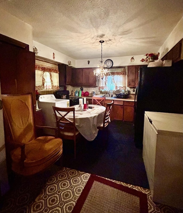 kitchen featuring washing machine and clothes dryer, light countertops, freestanding refrigerator, a notable chandelier, and a textured ceiling