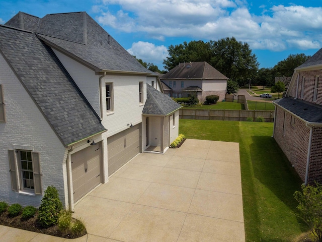 view of side of home with a garage, a yard, a shingled roof, and brick siding