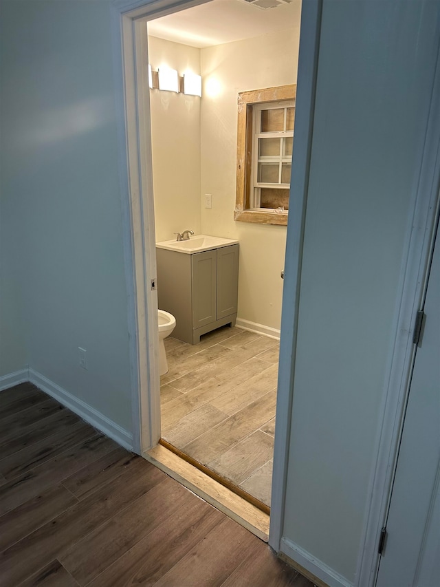 bathroom with wood-type flooring, vanity, and toilet