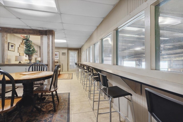 tiled dining space with a paneled ceiling