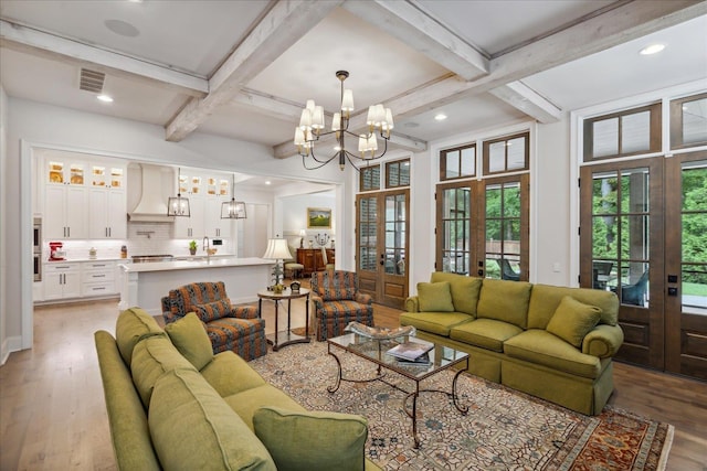 living room featuring coffered ceiling, light hardwood / wood-style floors, beam ceiling, and french doors