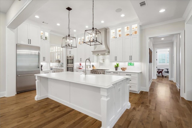 kitchen featuring backsplash, a kitchen island with sink, appliances with stainless steel finishes, and white cabinetry