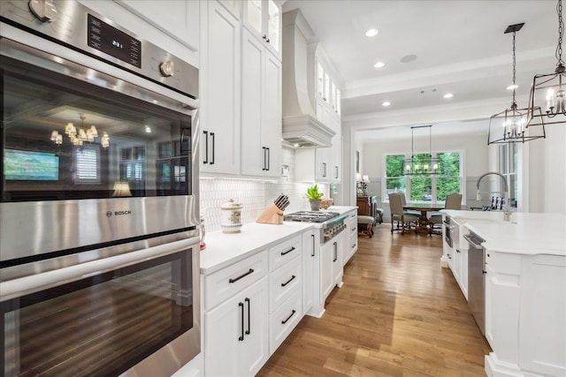 kitchen featuring white cabinetry, hanging light fixtures, stainless steel appliances, and custom exhaust hood