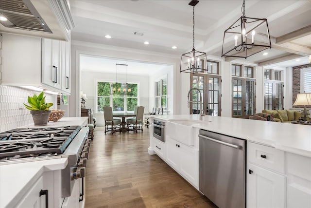 kitchen with extractor fan, sink, hanging light fixtures, appliances with stainless steel finishes, and white cabinets