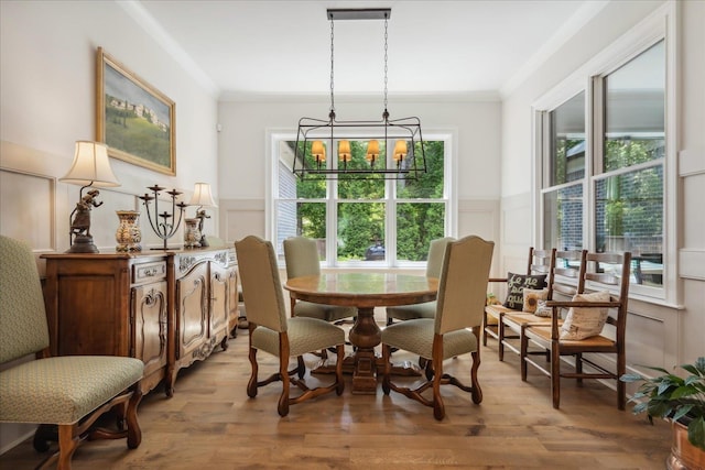 dining space featuring crown molding, a chandelier, a healthy amount of sunlight, and light hardwood / wood-style flooring